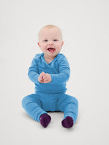 Iksplor baby wearing a blue merino wool long sleeve shirt and matching pants with fold-over mitts. #color_blue sky