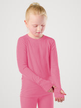 A young girl with blonde hair in a ponytail wearing a bright pink long-sleeve shirt and matching pink leggings, standing against a light gray studio background. #color_alpenglow