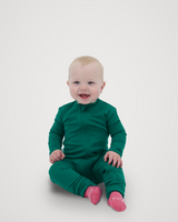 Baby smiling and sitting while wearing an evergreen Merino Wool Adventure Zippy romper with front zipper, paired with pink socks #color_evergreen