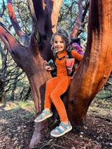 Young girl in bright orange merino wool outside in nature #color_poppy