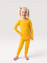Young girl wearing a yellow iksplor merino long sleeve base layer top with thumbholes on white background #color_yellowstone