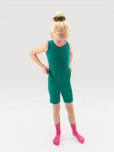 A young girl wearing an Iksplor green merino wool adventure tank top and matching shorts with bright pink socks. #color_evergreen