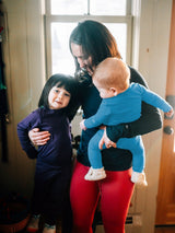 Iksplor mother holding a baby in a blue merino wool long sleeve shirt and toddler in a purple merino wool set . #color_blue sky