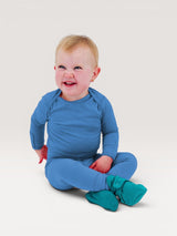Iksplor baby wearing a blue merino wool long sleeve shirt and matching pants with fold-over mitts. #color_blue sky