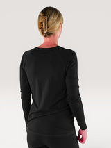 Back view of a woman wearing an Iksplor black merino wool long sleeve nursing top with thumb holes. #color_teton eclipse - black