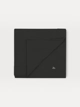 Iksplor Merino Wool Adventure Blanket in black, featuring a minimalist mountain logo, folded square. #color_teton eclipse