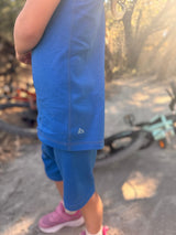 Iksplor kids blue merino wool adventure tank top with mountain logo detail worn outdoors on a sunny trail #color_ocean