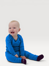 Happy baby wearing bright blue Iksplor merino wool leggings with a comfortable wide waistband #color_ocean