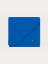 Iksplor blue merino wool adventure blanket folded neatly with a small embroidered mountain logo in the corner. #color_ocean