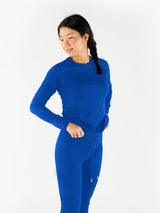 Woman wearing a bright blue Iksplor merino wool long sleeve top with a crew neck and fitted sleeves #color_ocean