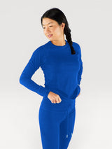 Woman wearing a bright blue Iksplor merino wool long sleeve top with a crew neck and fitted sleeves #color_ocean