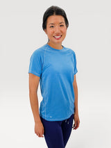 Woman wearing a blue Iksplor merino wool t-shirt with short sleeves and contrast stitching on a white background. #color_blue sky
