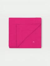 Iksplor fuchsia pink merino wool adventure blanket folded square with a small embroidered mountain logo detail. #color_peak pink