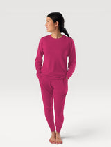 Woman wearing Iksplor fuchsia pink merino wool adventure joggers and matching long sleeve top, slim fit design. #color_peak pink