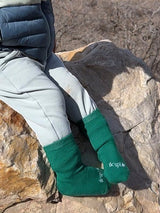 Iksplor green merino wool and tencel blend trail socks worn by a child sitting on a rock outdoors. #color_jungle trek