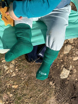 Iksplor green merino wool and tencel blend trail socks worn by a toddler sitting in a camping chair outdoors. #color_jungle trek