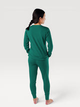Woman wearing Iksplor dark green merino wool adventure joggers and matching long sleeve top from behind #color_evergreen