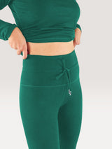 Iksplor forest green midweight merino wool leggings with a high-waisted drawstring band worn by a woman. #color_evergreen