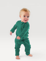 Iksplor baby wearing a green merino wool zip romper with long sleeves and snug cuffs on a white background #color_evergreen