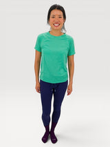 Woman wearing a bright green Iksplor merino wool t-shirt with short sleeves, standing against a white backdrop. #color_meadow