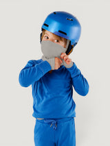 Child wearing an Iksplor grey merino wool balaclava with a blue helmet and matching blue long-sleeve shirt #color_trail dust