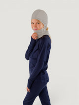 Iksplor grey merino wool balaclava with ponytail hole worn by a child in a navy base layer set #color_trail dust