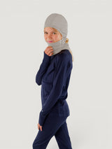 Iksplor grey merino wool balaclava with ponytail hole worn by a child in a navy base layer set #color_trail dust