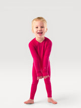 Iksplor kids merino wool long sleeve top in vibrant pink worn by a smiling young girl on a white background #color_peak pink