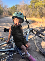 Child wearing an Iksplor black merino wool adventure tank top and matching shorts while sitting on a mountain bike. #color_teton eclipse