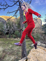 Iksplor kids merino wool long sleeve top and matching leggings in bright red worn by a child jumping outdoors. #color_campfire