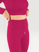 Iksplor magenta merino wool baselayer leggings with a high-waisted drawstring fit worn by a person. #color_peak pink