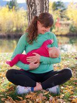 Iksplor merino wool nursing sun hoodie in mint green worn by a mother breastfeeding her baby outdoors in autumn #color_meadow