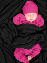 Iksplor merino wool adventure blanket in black wrapped around a newborn baby wearing a bright pink outfit and hat #color_teton eclipse