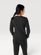 Woman wearing a black Iksplor Merino Wool Adventure Crew long-sleeve shirt, back view, against a plain background. #color_teton eclipse