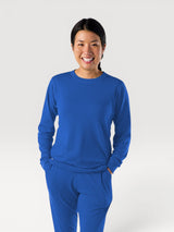 Woman wearing a bright blue Iksplor Merino Wool Adventure Crew long-sleeve shirt with a comfortable, breathable fit #color_ocean
