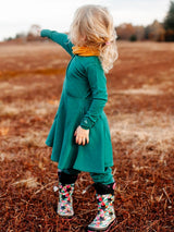 Iksplor kids merino wool adventure dress in forest green with pockets, worn by a child in a field. #color_evergreen