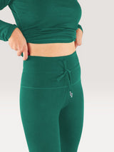 Iksplor forest green merino wool baselayer leggings with a high-waisted drawstring fit worn under a matching top. #color_evergreen