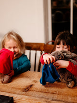 Two children playing with plush toys while wearing soft Iksplor merino wool underwear in blue and red #color_peak pink