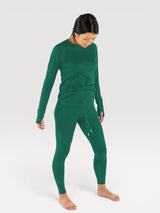 Woman wearing Iksplor forest green merino wool long sleeve top and matching leggings with thumbholes #color_evergreen