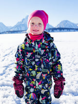 Child wearing a bright pink Iksplor merino wool neck gaiter and winter gear in a snowy mountain landscape. #color_peak pink