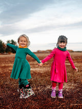 Two young girls wearing Iksplor merino wool neck gaiters in mustard yellow and forest green outdoors. #color_yellowstone