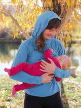 Iksplor blue merino wool nursing sun hoodie worn by a mother breastfeeding her baby outdoors in autumn #color_blue sky
