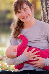 A mother wearing an Iksplor merino wool long sleeve nursing top while holding her baby outdoors in autumn. #color_trail dust
