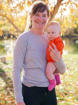 Iksplor merino wool long sleeve nursing top in light grey worn by a mother holding her baby outdoors. #color_trail dust