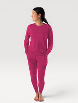 Woman wearing a vibrant pink Iksplor Merino Wool Adventure Crew long-sleeve top and matching joggers #color_peak pink