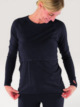 Woman wearing a navy blue Iksplor merino wool long sleeve nursing top with thumb holes and discreet access. #color_starry night