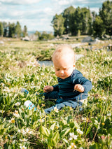 Iksplor baby wearing a navy blue merino wool long sleeve shirt sitting in a sunny wildflower meadow #color_starry night