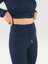 Iksplor navy blue merino wool baselayer leggings with a high-waisted drawstring fit worn by a woman. #color_starry night - navy