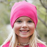 A young girl wearing a bright pink Iksplor merino wool beanie, designed for comfort and warmth. #color_peak pink