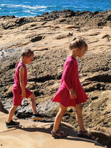 Two girls in Iksplor pink merino wool clothing walking on rocky coastal terrain near the ocean. #color_peak pink